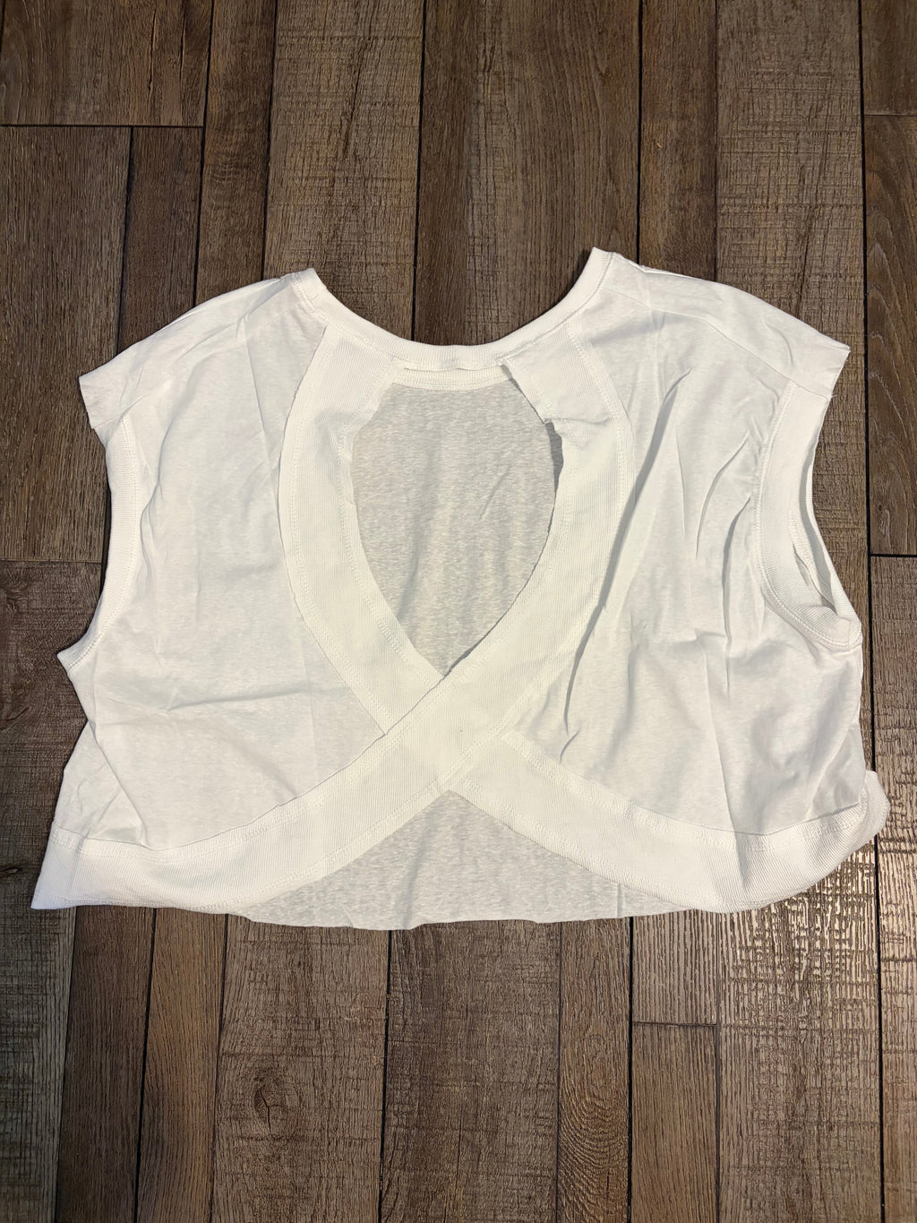 White t-shirt with a large circular cutout on a wooden surface
